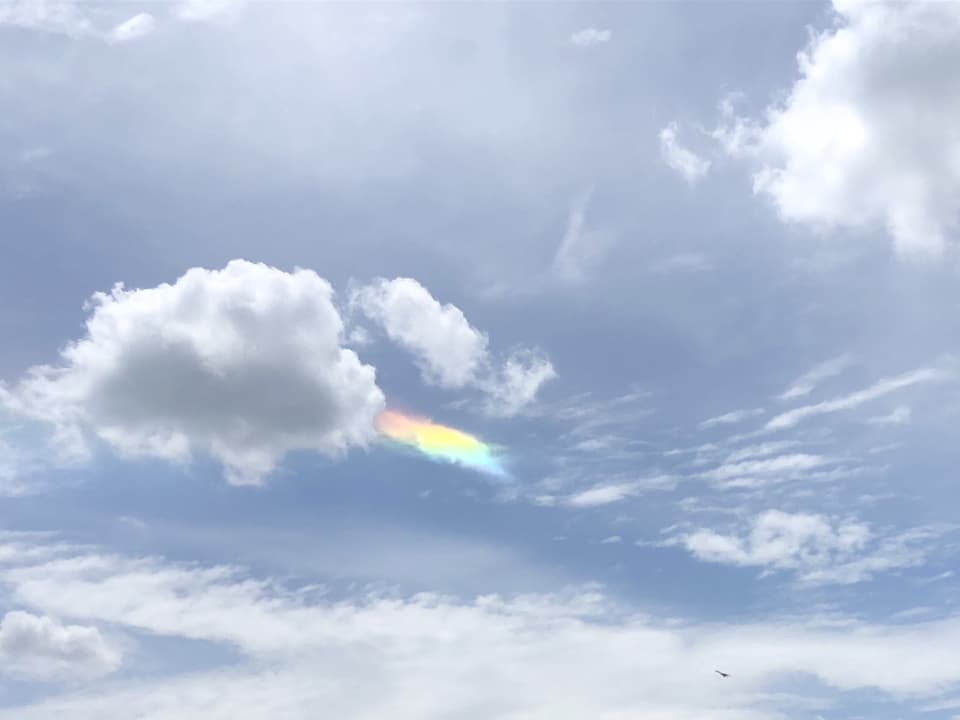 Himmel mit verschiedenen Wolken, auch in Regenbogenfarbe.