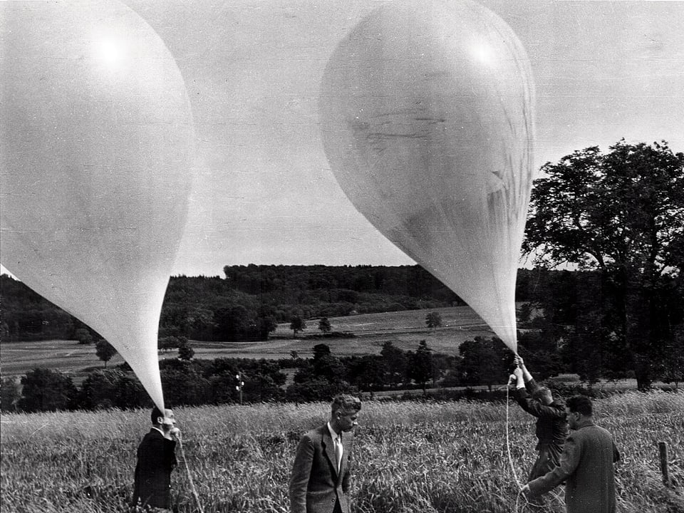Männer lassen in einem Feld Ballone steigen.