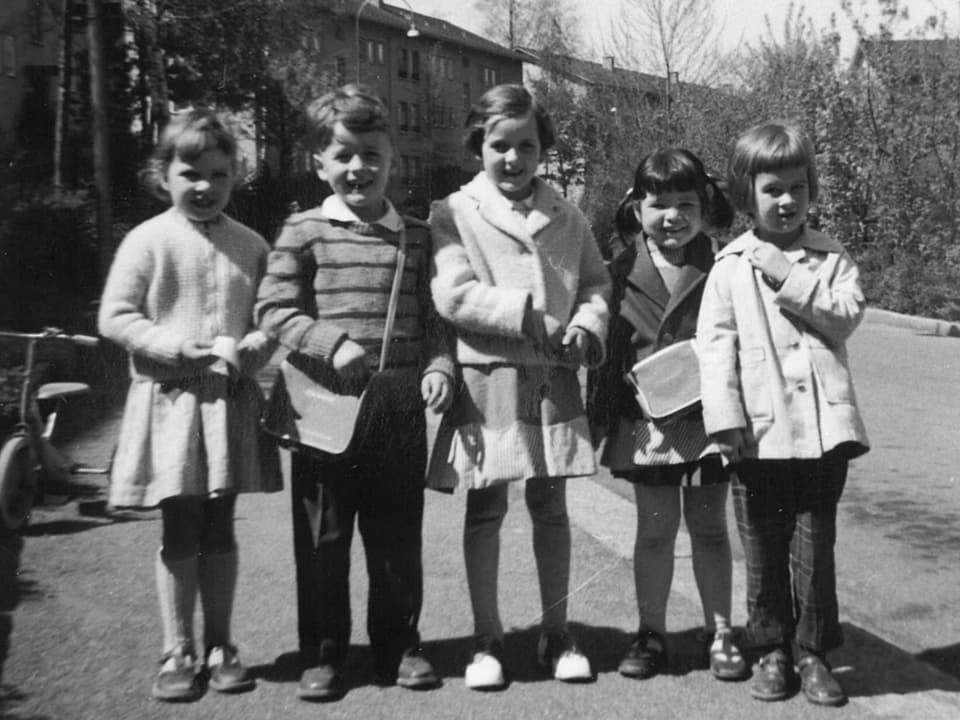 Kinder posieren auf dem Trottoir mit kleinen Pausensäckli über der Schulter.