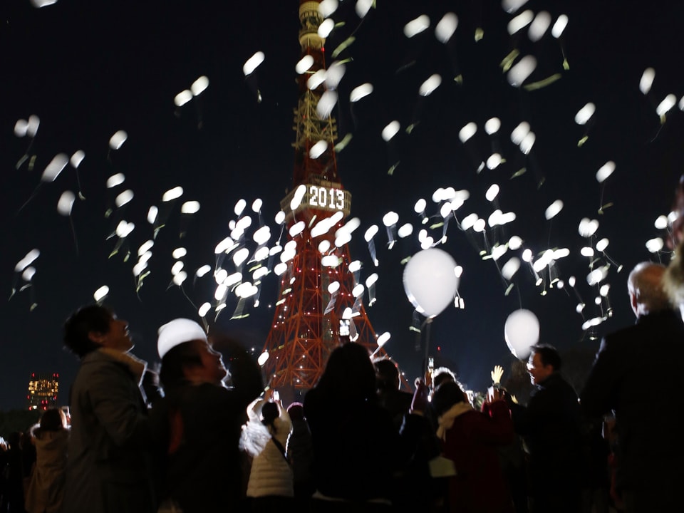 Menschen in Tokio lassen zum Jahreswechsel weisse Ballone in den Himmel steigen. Im Hintergrund ist der Tokyo Tower. (reuters)