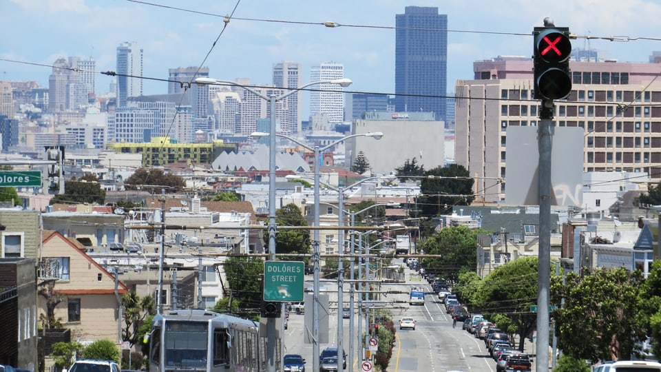 Strasse in San Francisco mit roter Ampel und Wolkenkratzern im Hintergrund.
