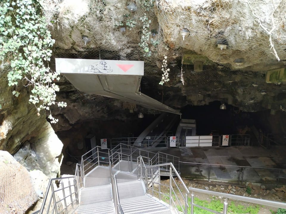 Treppen hinunter in eine Höhle mit einem See.