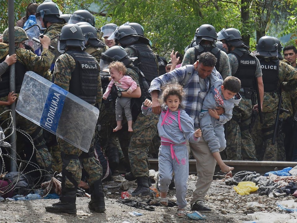 Eine Polizeikette versucht, Flüchtlinge vom Grenzübertritt nach Mazedonien aufzuhalten