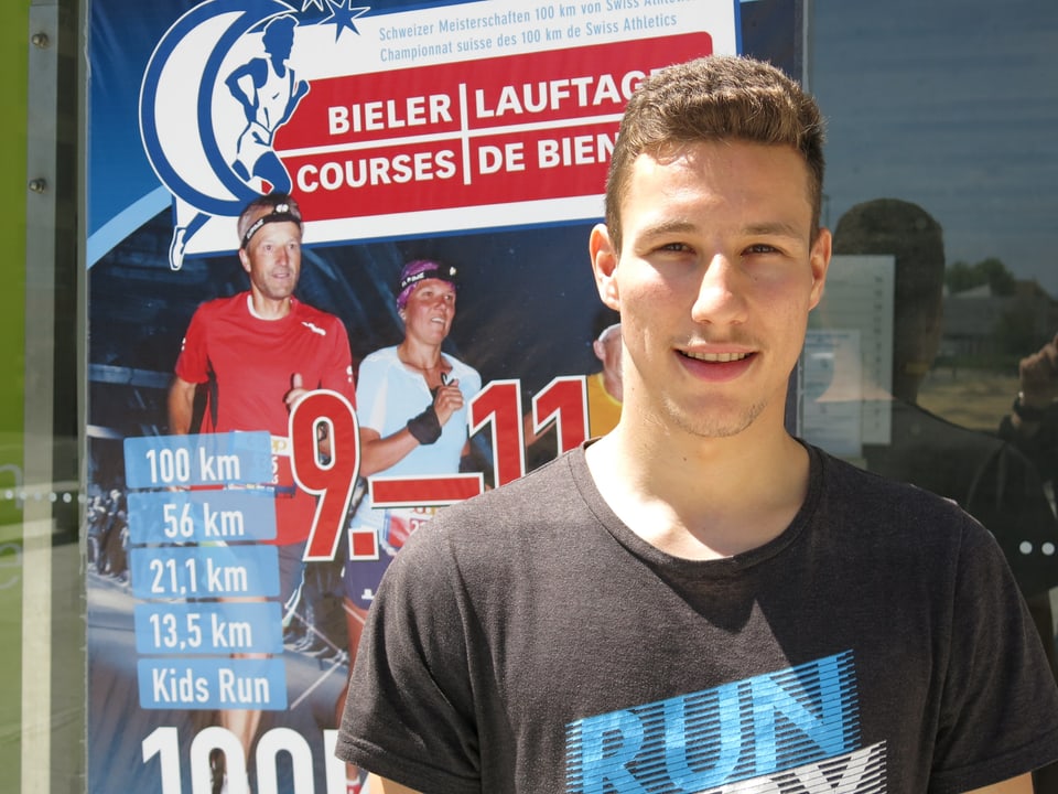 Yannick Oberson vor dem Plakat des 100-km-Laufes.