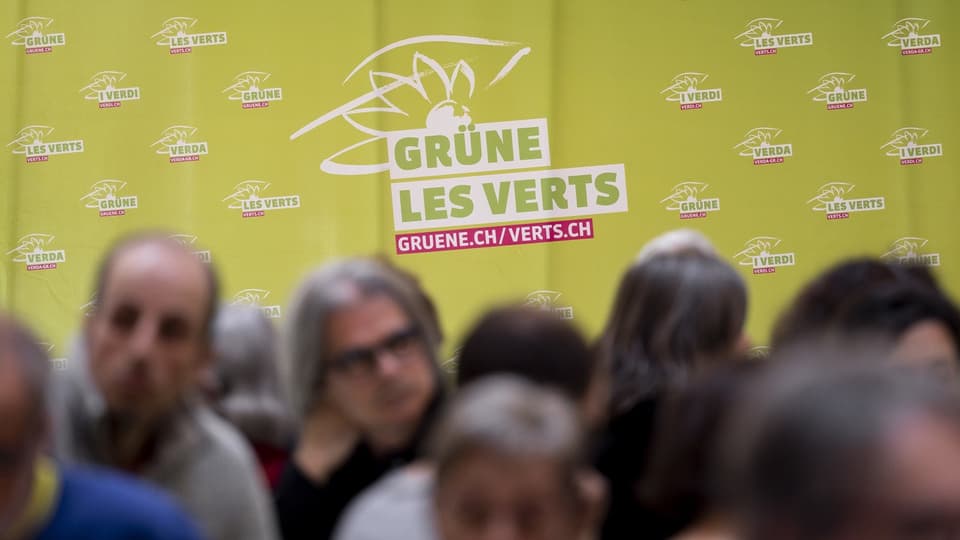 Menschen stehen für einem Logo der Grünen-Partei der Schweiz.