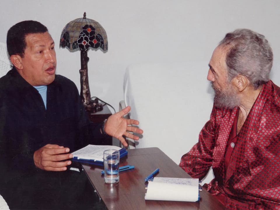 Castro und Chàvez sprechen miteinander an einem Tisch sitzend