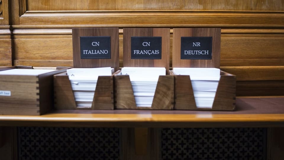 Schreibkarten mit dem Nationalratslogo in drei Landessprachen im Nationalratssaal.