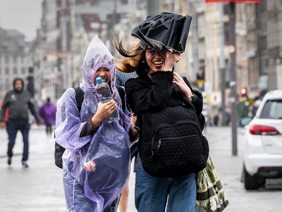 Touristinnen in Amsterdam trotzen den Sturmböen. 