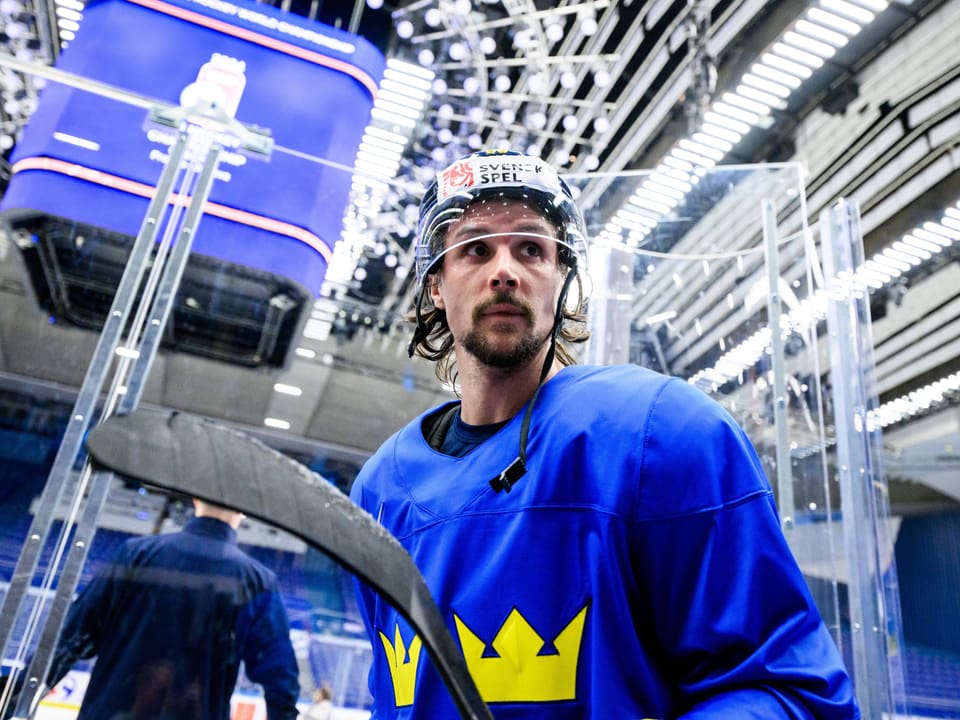 Eishockeyspieler in blauem Trikot mit Helm auf dem Eisfeld