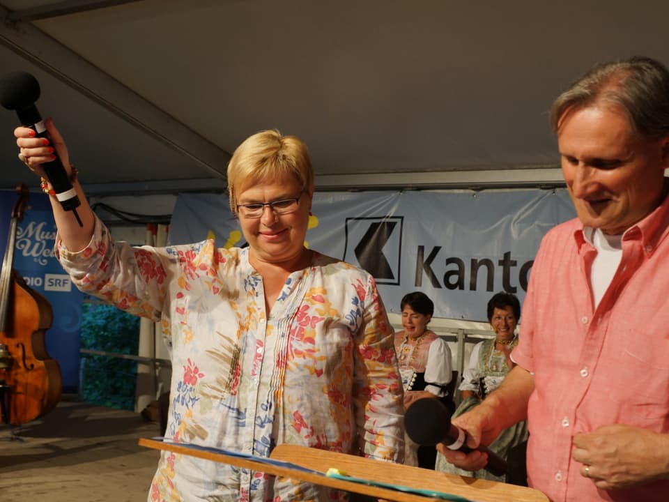 Christine Gertschen hält das Mikrophon in die Höhe um die Geräuschkulise im Saal festzuhalten.