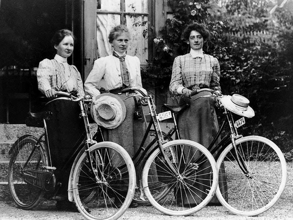 Schwarzweissbild: Drei Frauen mit Fahrrädern.