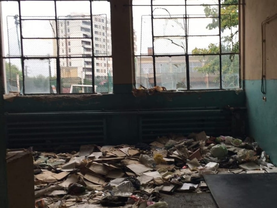 Blick in einen Schulraum, am Boden liegt Müll, eine Wandtafel ist heruntergefallen.