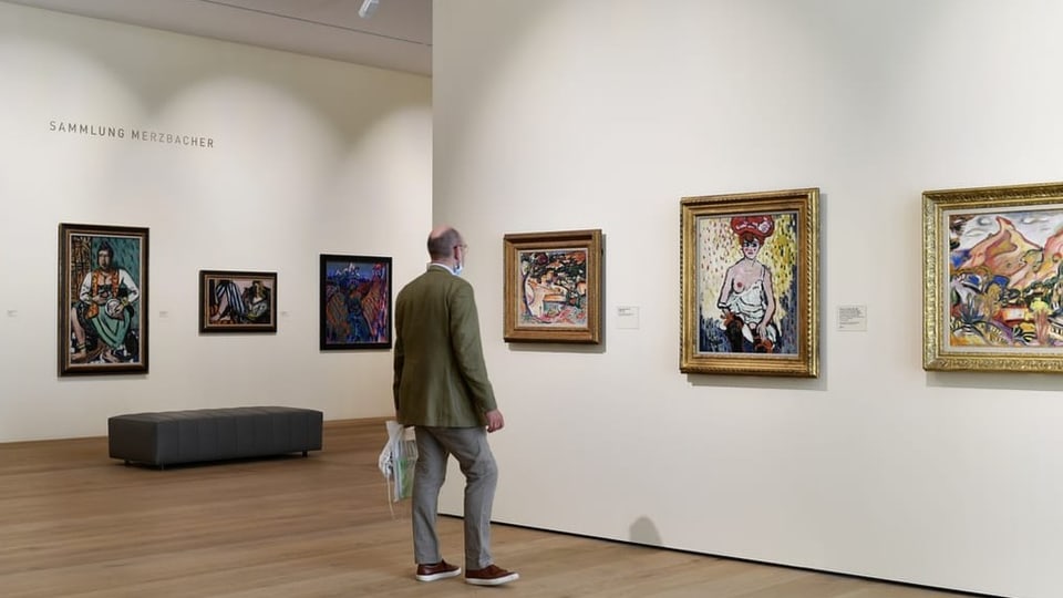 ein Mann steht vor mehreren Gemälden