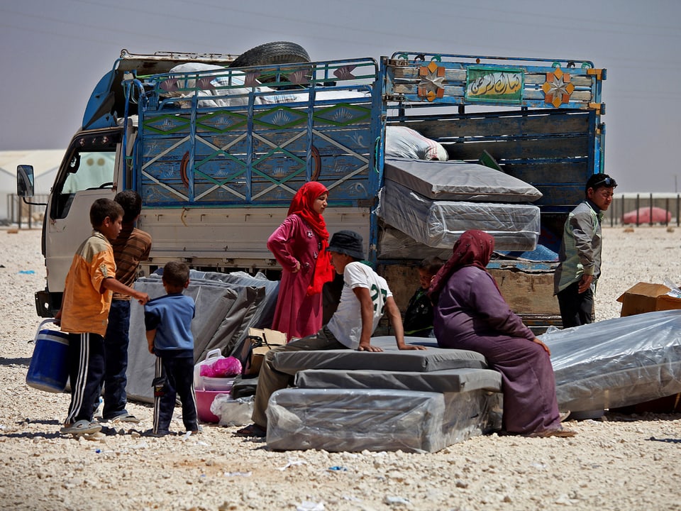 Flüchtlinge entladen ihre Habseligkeiten von einem LKW