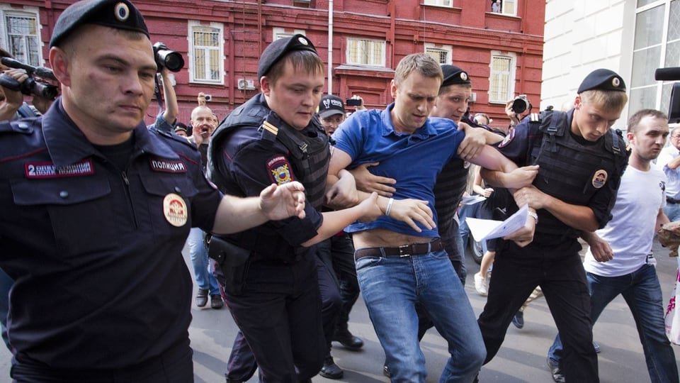 Nawalny wird von Polizisten abgeführt. 