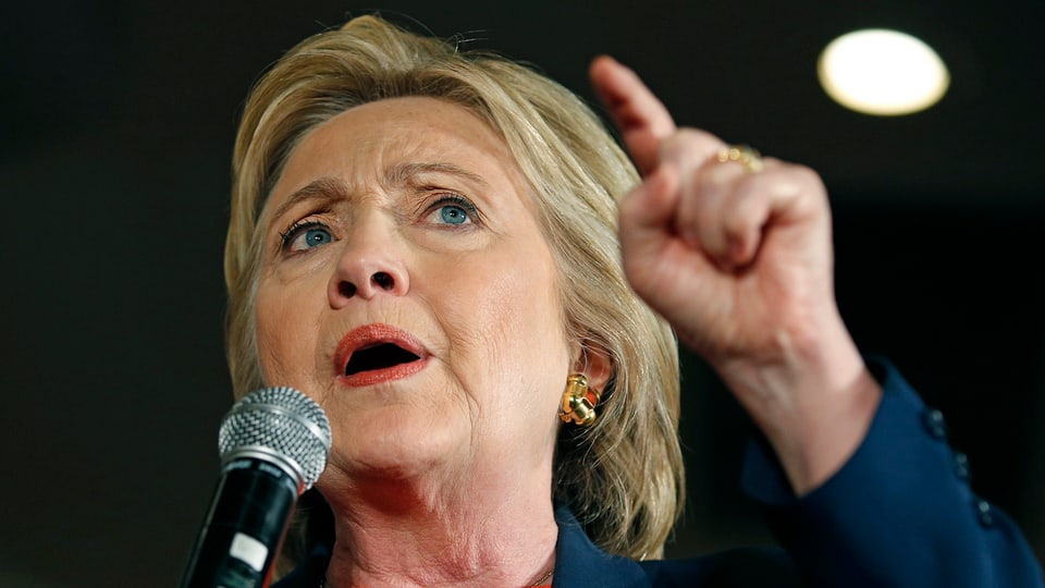 Clinton im Porträt mit gehobenem Zeigfinger.