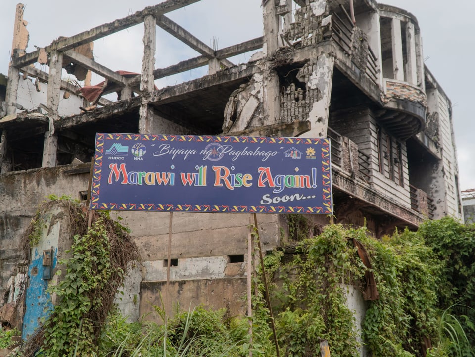 Plakat vor zerstortem Haus: «Marawi will Rise Again! Soon...»