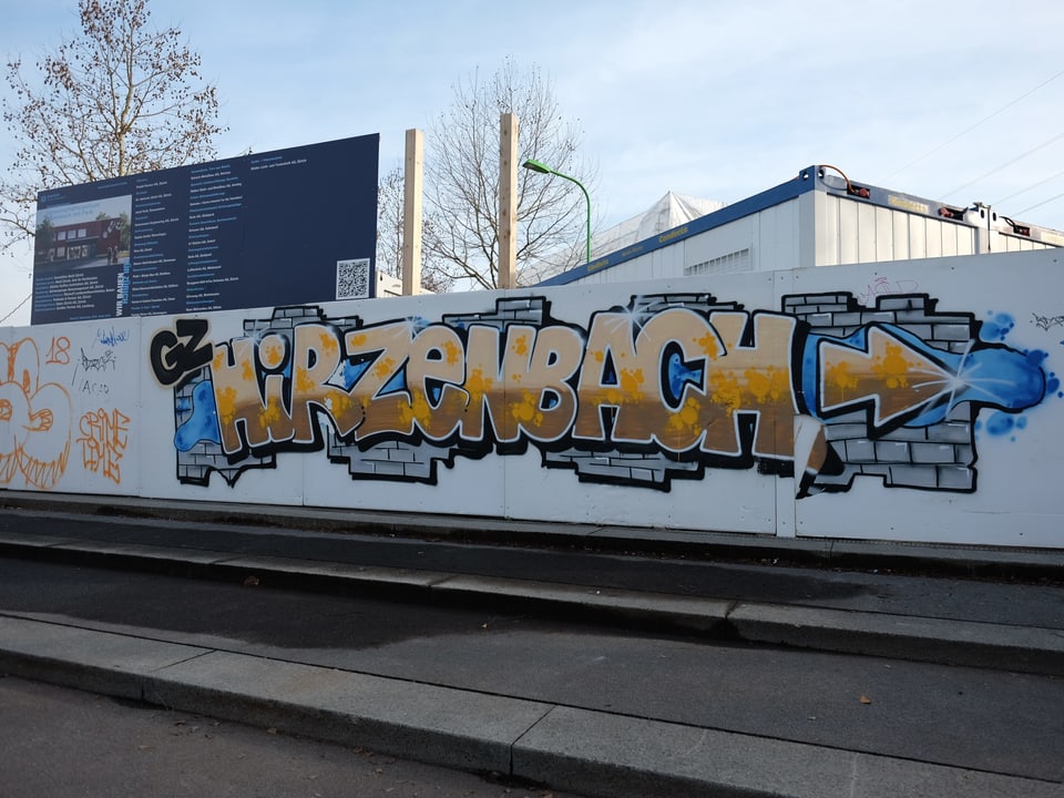 Auf einer weissen Wand vor der Baustelle steht in Graffiti-Schrift «Hirzenbach» geschrieben.
