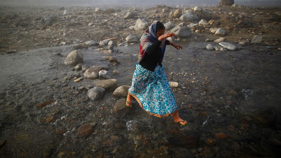 Frau hüpft über Steine über Fluss