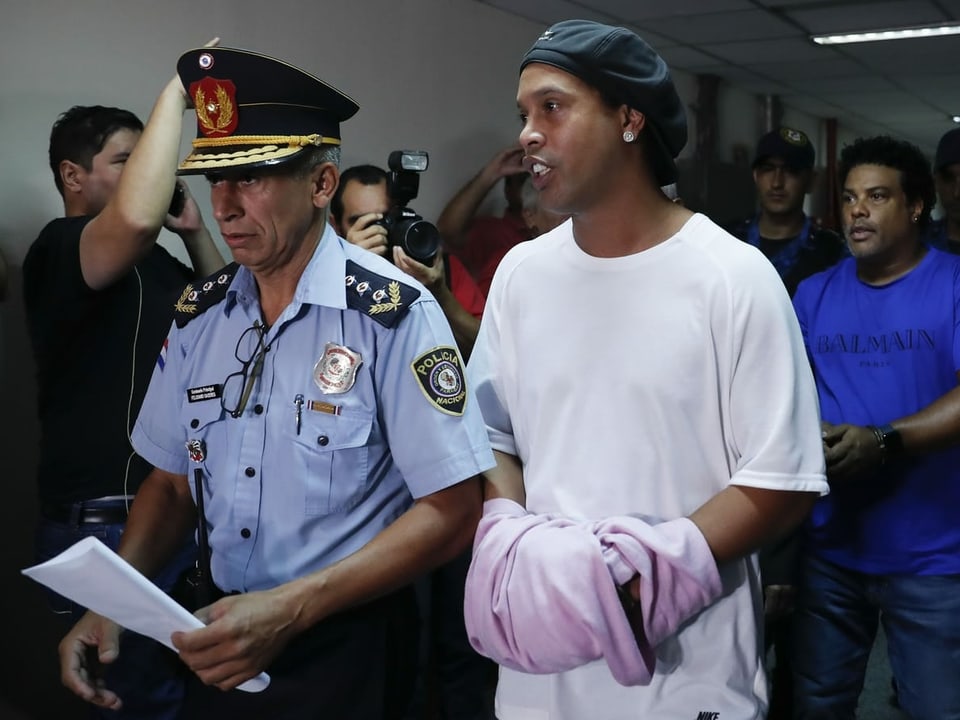 Ronaldinho wird in Asuncion von einem Polizisten aus dem Gericht eskortiert.