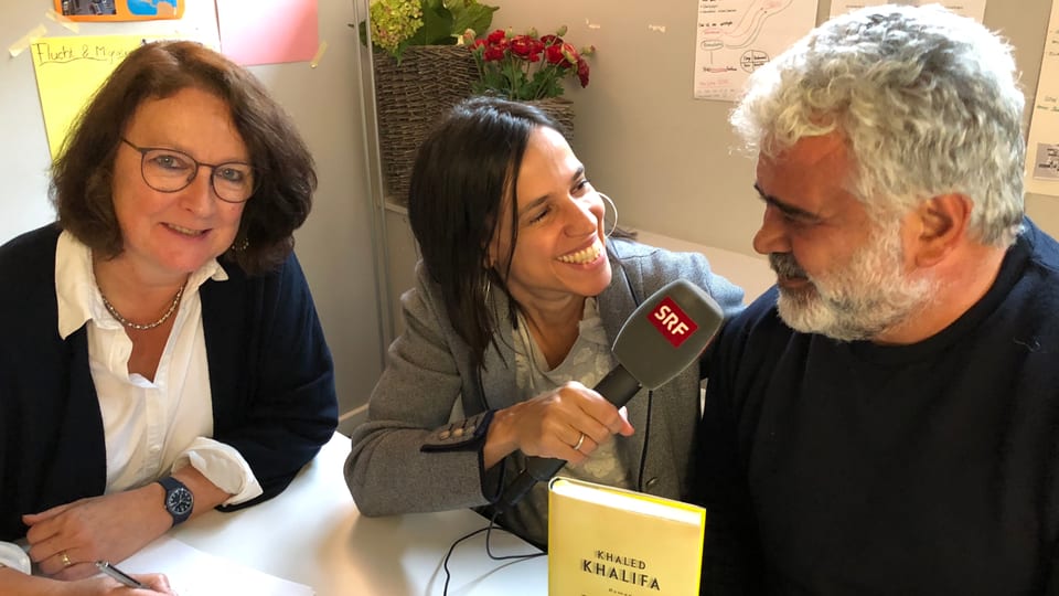 Annette König sitzt neben Khaled Khalifa an einem Tisch und interviewt ihn