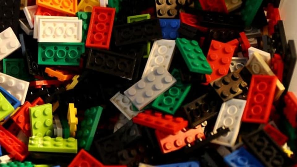 Viele farbige Legosteine in einer Box mit Hand