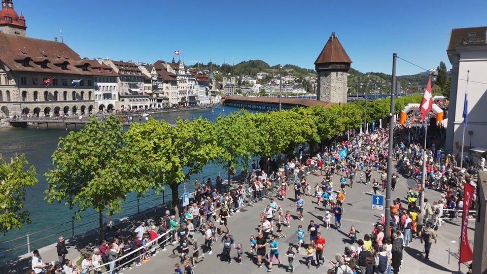 Läuferinnen und Läufer rennen vor der Kappelbrücke in Luzern vorbei.