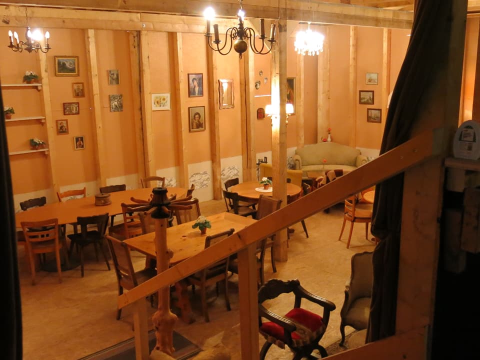 Eine Stube mit mehreren Tischen und Bildern an der Wand. 