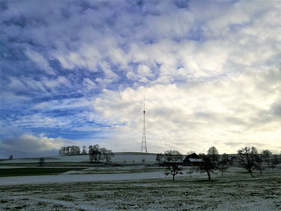 Sendeturm Beromünster mit einigen Schleierwolken und Sonnenstrahlen am Himmel.