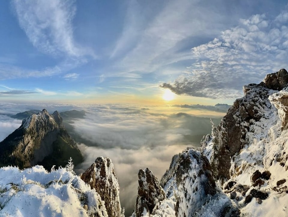 Sonnenaufgang von einem Gipfel aus. Unten Nebelmeer, darüber auch einige Wolken. 