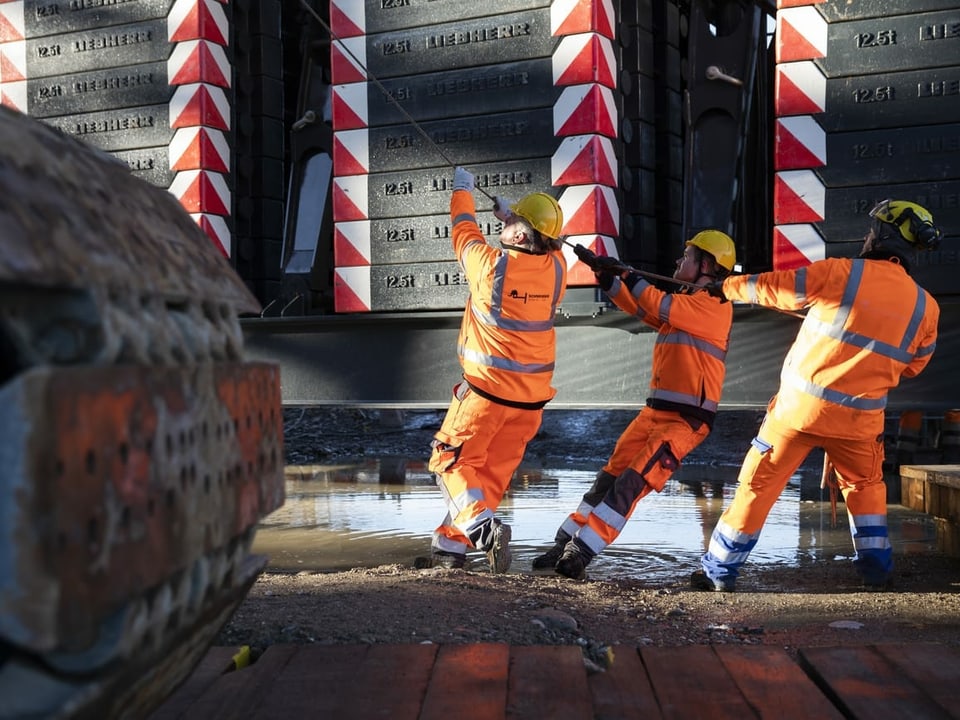 Bauarbeiter richten mit einem Seil die 340 Tonnen schwere Stahlbrücke aus.