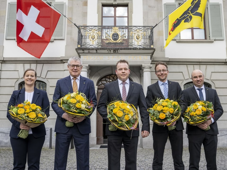 Vier Männer und eine Frau halten gelbe Blumensträusse.