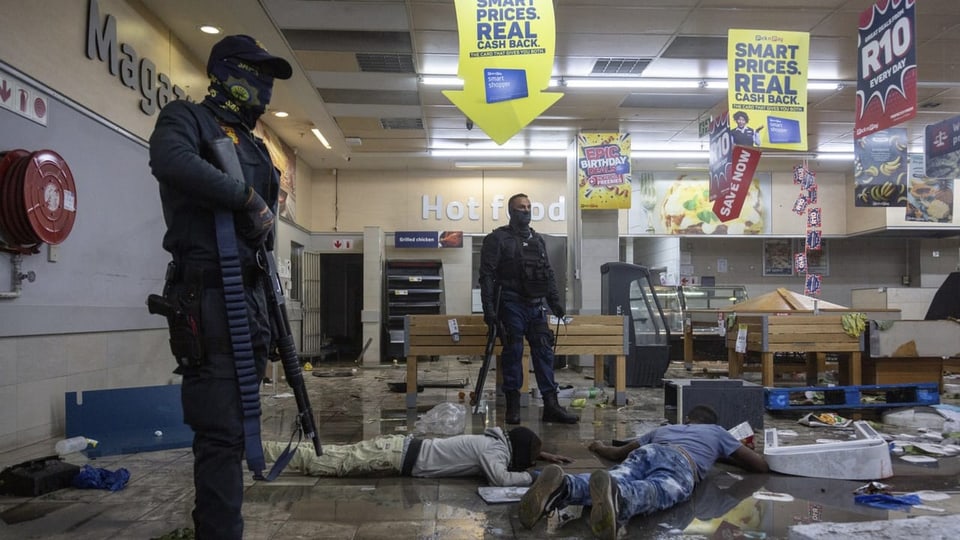 Plünderer mit Polizisten in einem Einkaufszentrum in Alexandra Township