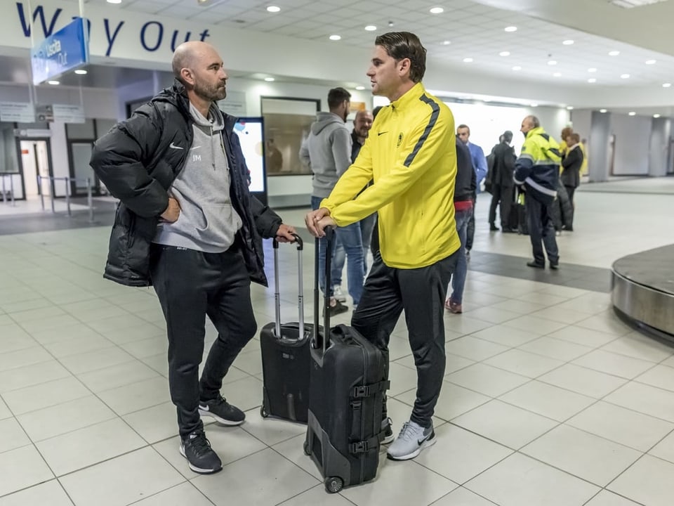 Joël Magnin und Gerardo Seoane stehen am Flughafen mit je einem Koffer.