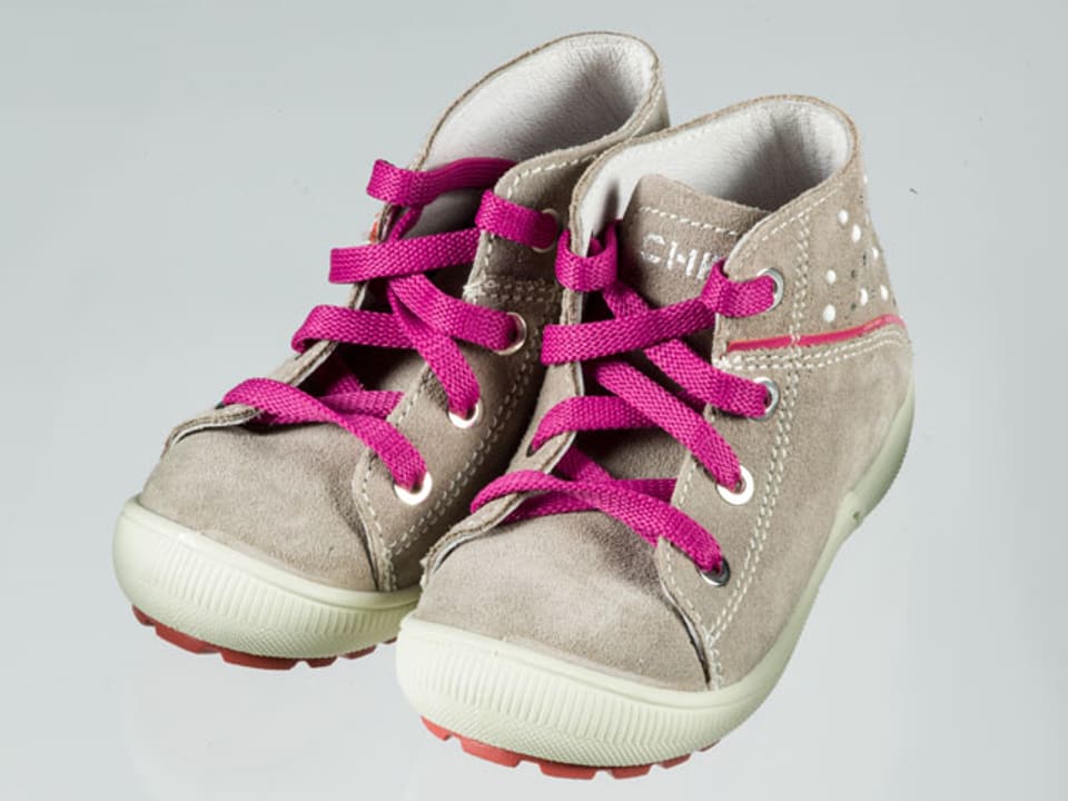 Ein paar graue, hohe Kinderschuhe mit pinken Schuhbändeln.