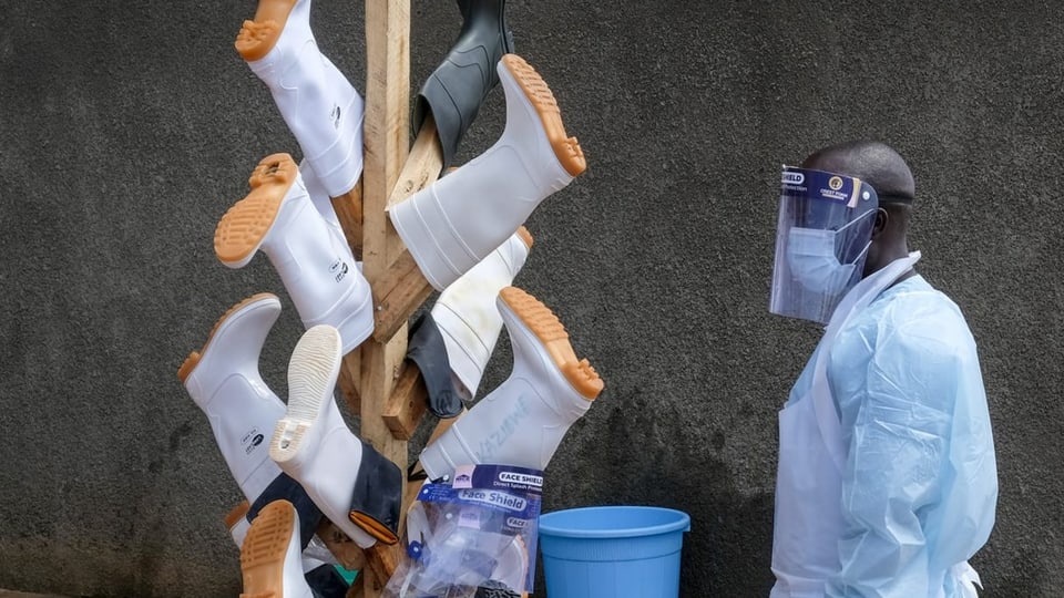 Ein Mann in Schutzkleidung steht vor einem Turm auf dem Gummistiefel getrocknet werden.