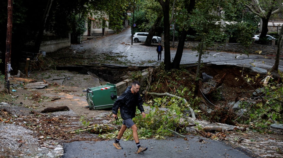 Ein Mann läuft im Dorf Ano Meria in der Nähe von Volosan einer zerstörten Strasse vorbei. 