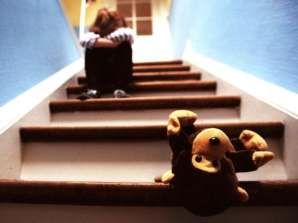 Kind auf einer Treppe, heruntergefallenes Plüschtier.