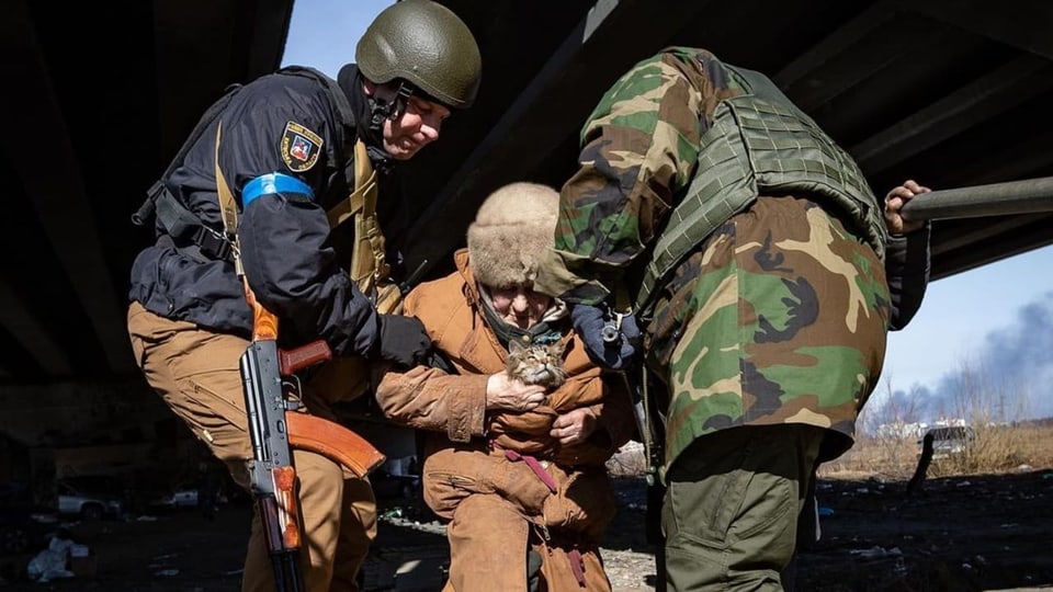 Eine Grossmutter versucht ihre Katze zu retten während ukrainische Helfer versuchen die Frau zu retten.
