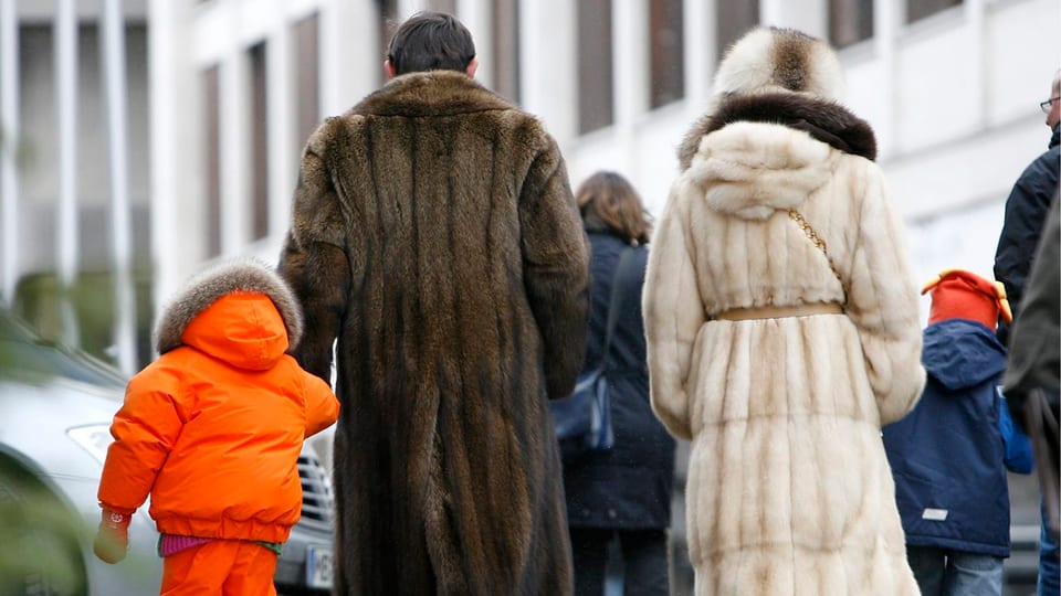 Wohlhabende Gäste in edlen Pelzmänteln auf der Strasse in St. Moritz von hinten gesehen.
