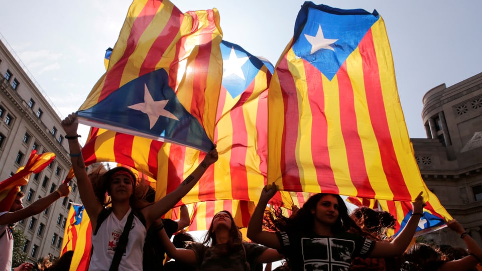 Junge Frauen schwenken Katalonien-Flaggen.
