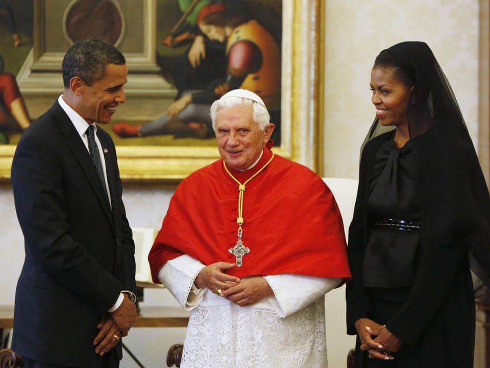 Der Papst steht zwischen den Obamas, die schwarz tragen. Michelle Obama trägt einen Schleier.