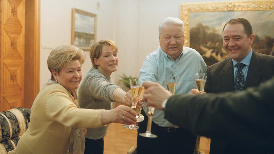 Eine Gruppe von Menschen, darunter Jelzin, stossen feierlich an mit einem Getränk.