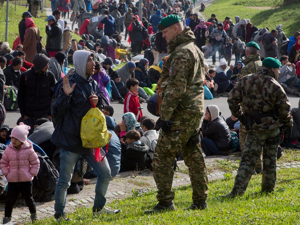 Soldaten neben Flüchtlingen. 