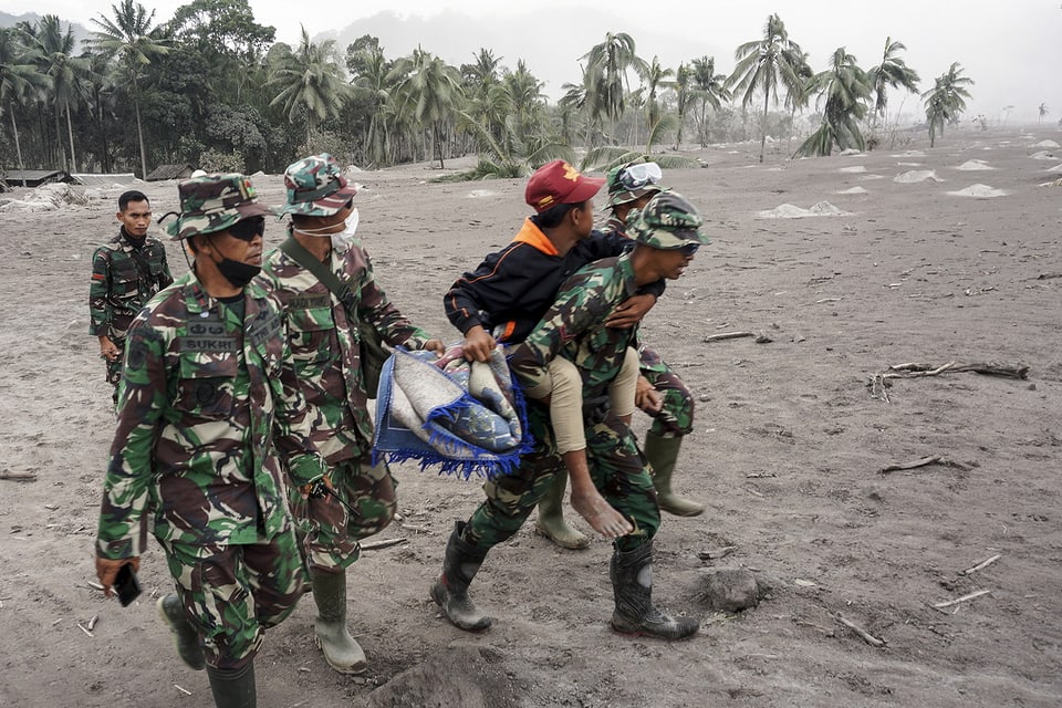 Armeeangehörige evakuieren einen Dorfbewohner aus einem vom Ausbruch des Vulkans Semeru betroffenen Gebiet.