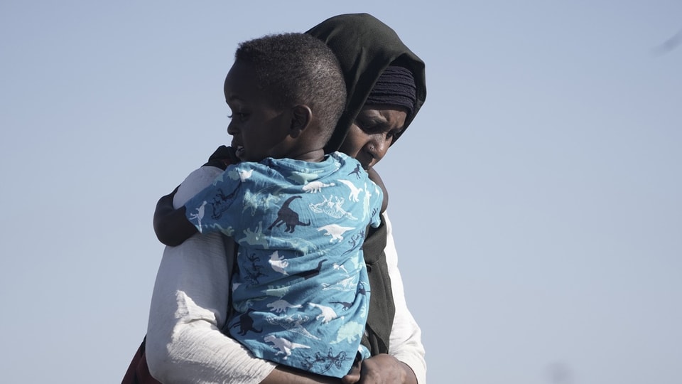 Eine sudanesische Evakuierte trägt ihren Sohn.
