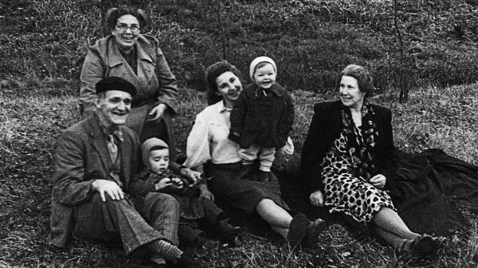 Familie mit zwei Kindern sitzt auf Rasen