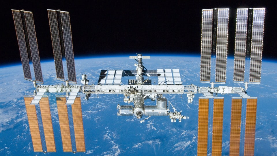 Ein Bild der Internationale Raumstation ISS auf dem im Hintergrund die Erde zu sehen ist.