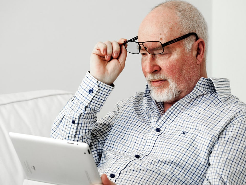Lesender Mann hebt ungläubig seine Brill