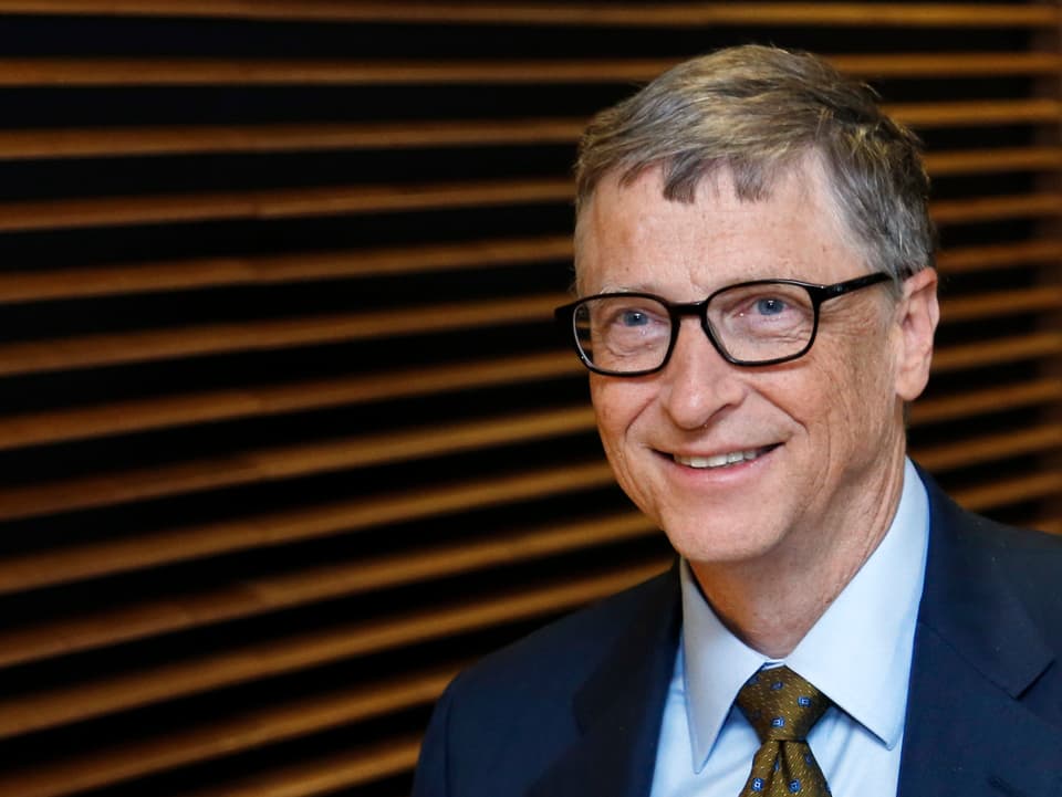 Bill Gates mit Brille lächelt in die Kamrea.